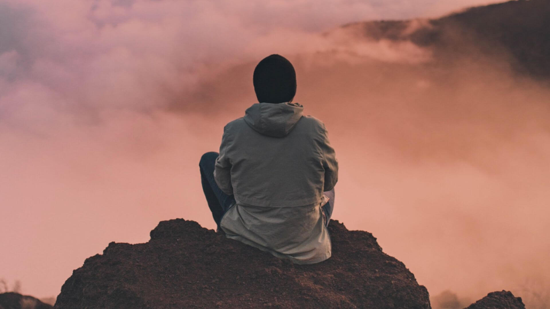 A man sits and contemplates pink clouds